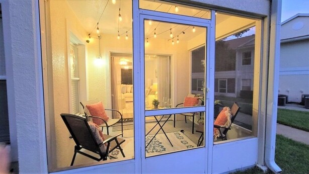 A cozy patio with a table and chairs, a glass door, and string lights. - Refreshed 3BR condo- pool/patio/tennis - 1st Floor (Four Corners)