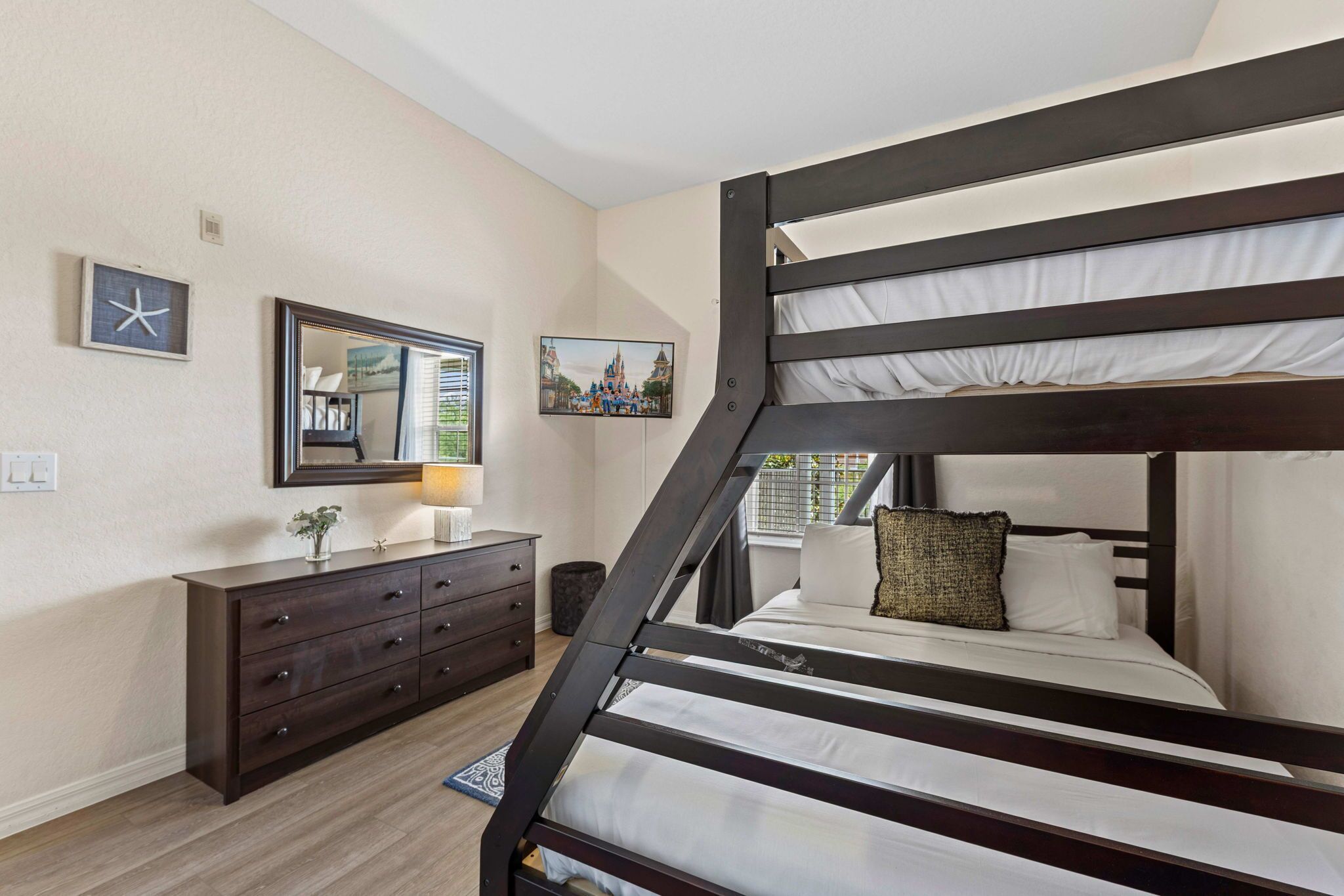 Ein Schlafzimmer mit Etagenbett, Kommode, Spiegel und Wandbildern.