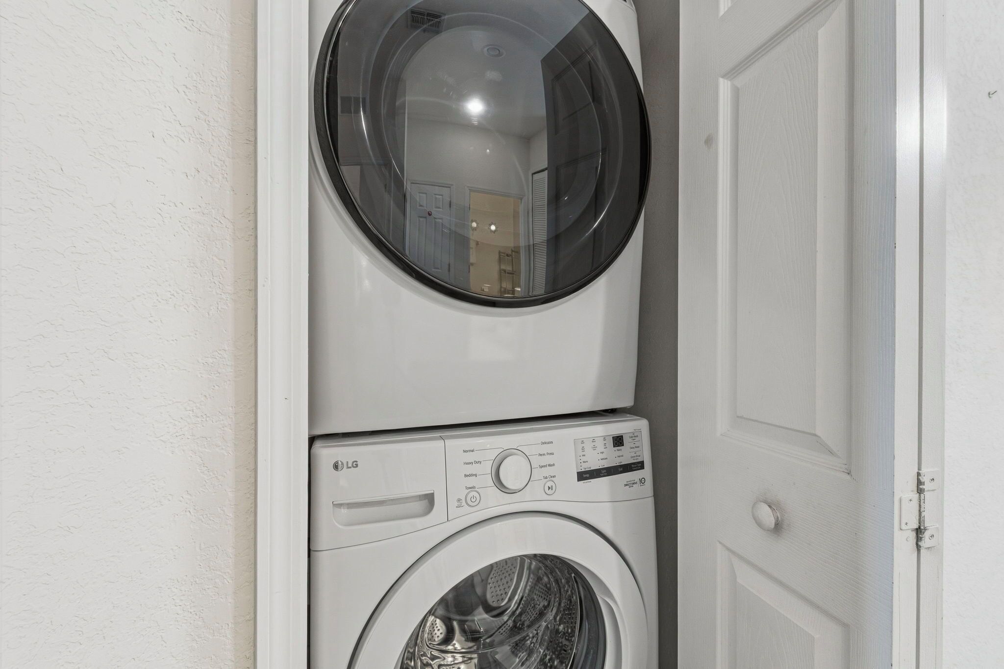 A stacked washer and dryer unit against a white wall.
