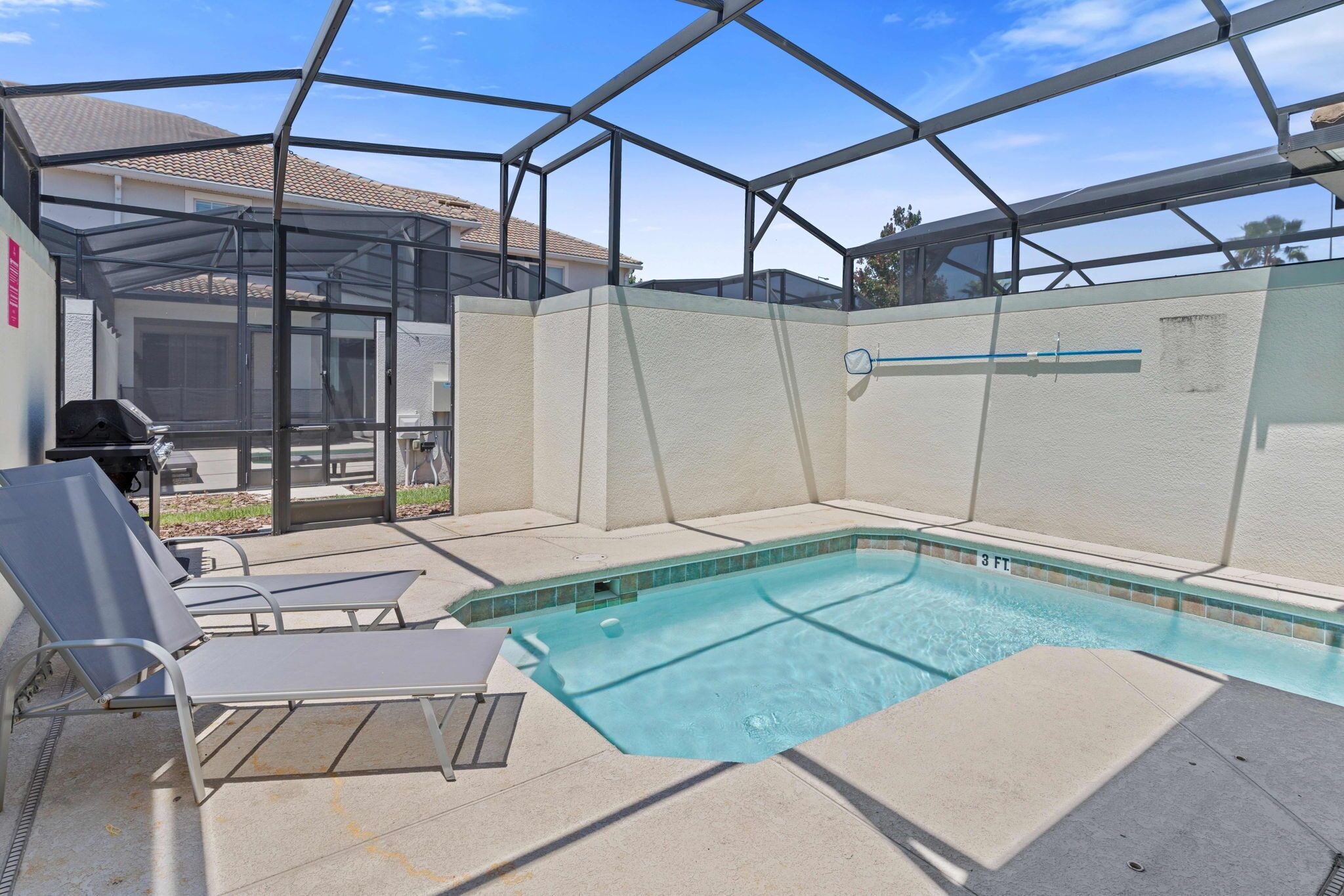 Une piscine extérieure couverte, dotée de chaises longues, d’un barbecue et d’un espace patio.