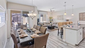 A spacious living area with a dining table set for four, a sofa, and a kitchen island.