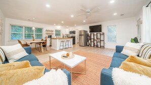 A spacious living area with a kitchen, dining area, and a large TV.