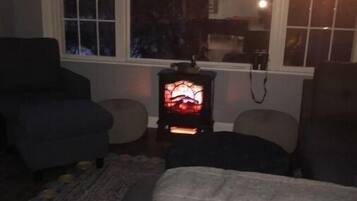 Ein gemütliches Wohnzimmer mit Kamin, Sofa und Sessel.
