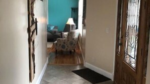 A hallway with a tiled floor, a wooden door with a decorative glass panel, and a blue wall in the background.