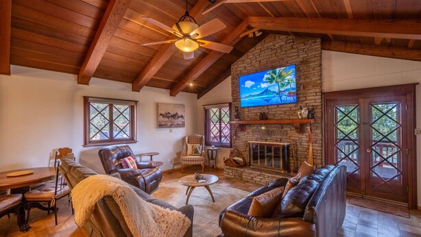 A spacious living room with a stone fireplace, leather sofas, and a ceiling fan. - Private property, located on a cul-de-sac, jacuzzi, deck, outdoor activities (Alto)