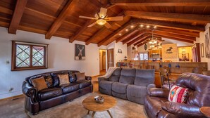 A spacious living room with a high ceiling and wooden beams, featuring two leather sofas, a round coffee table, and a fireplace. - Private property, located on a cul-de-sac, jacuzzi, deck, outdoor activities (Alto)