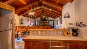 A kitchen with wooden cabinets, a tiled backsplash, and a stone fireplace. - Private property, located on a cul-de-sac, jacuzzi, deck, outdoor activities (Alto)