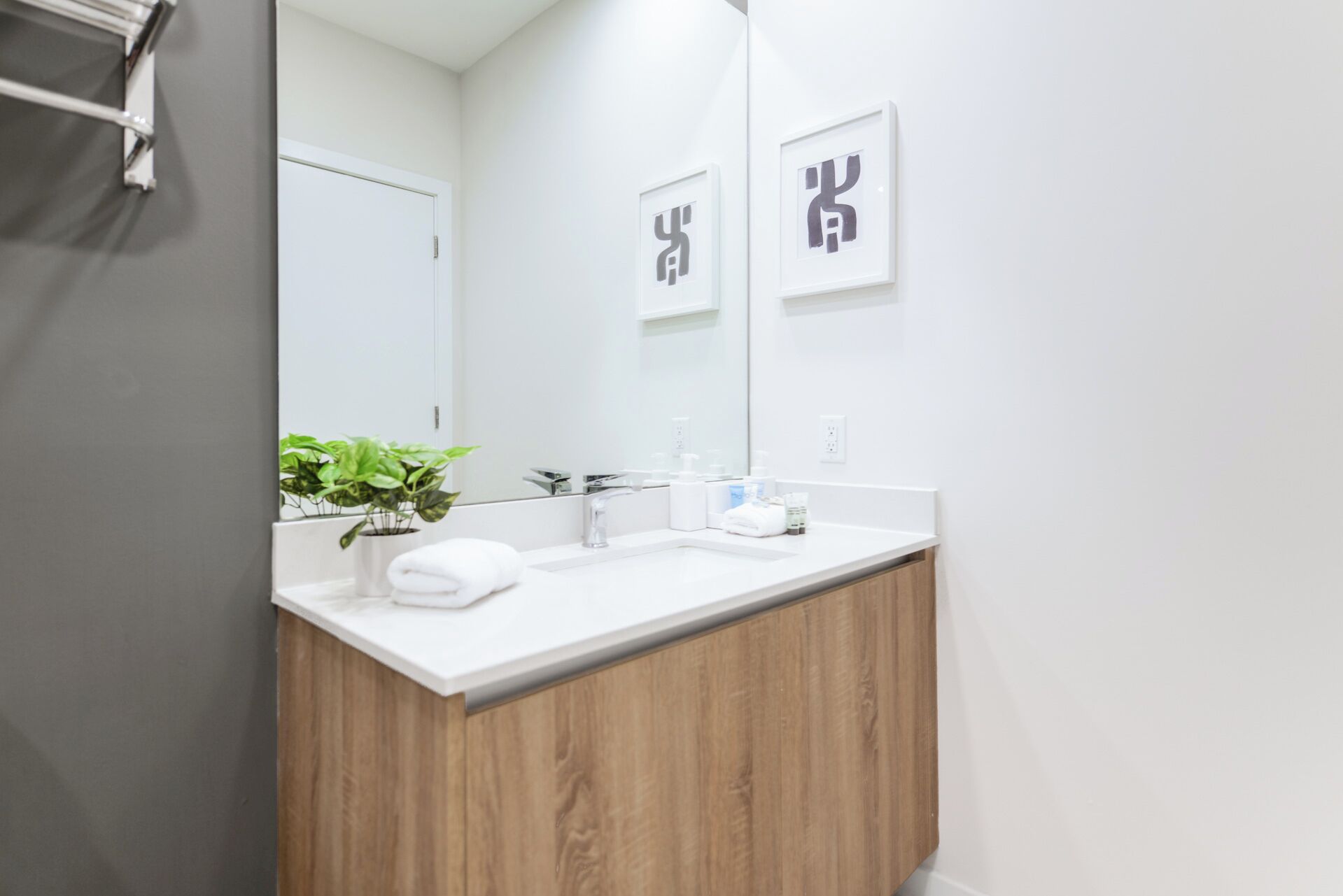 Un bany modern amb un tocador de fusta, un lavabo blanc i un mirall gran.