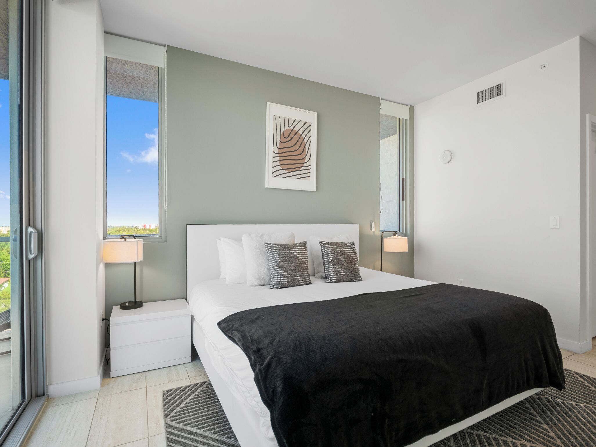 Une chambre moderne avec un grand lit, une vue sur la ville et un balcon.