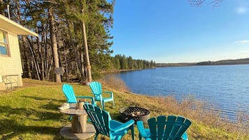 Relax by the serene lake with a fire pit and Adirondack chairs.