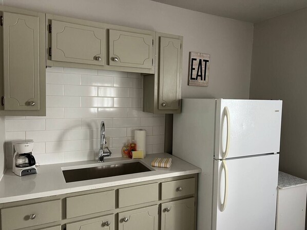 A kitchen with white cabinets, a sink, a coffee maker, and a refrigerator. - Corporate Cottage in LaPorte Cable St Front unit (La Porte)