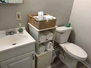 A bathroom with a white sink, a toilet, and a wicker basket on a shelf. - Corporate Cottage in LaPorte Cable St Front unit (La Porte)