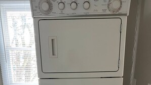 En vit tvättmaskin och torktumlare som är placerade ovanpå varandra, med ett fönster ovanför torktumlaren.