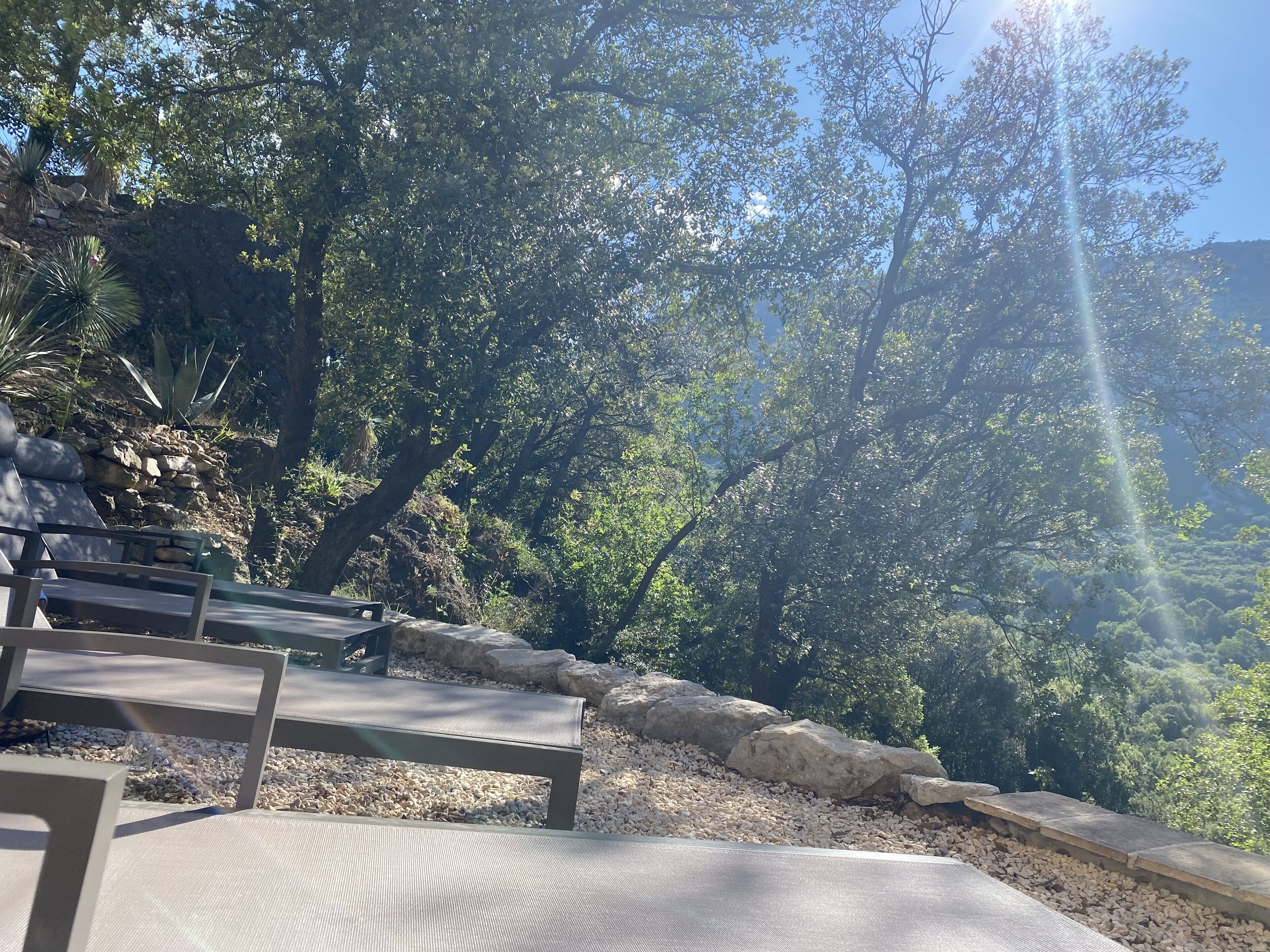 Un espace extérieur aménagé avec des sièges et une vue sur une colline rocheuse et des arbres.
