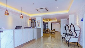 A hotel reception area with a marble floor, a reception desk, pendant lighting, and a seating area with chairs. - Hotel Dafam Enkadeli Thamrin Jakarta (Jakarta)