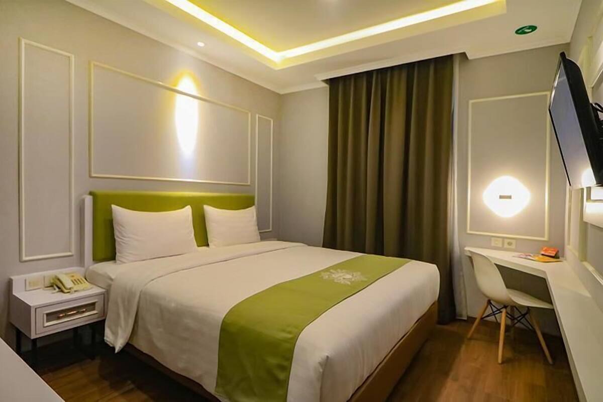 Une chambre d’hôtel comprenant un lit, une table de chevet, un bureau, une chaise et un téléviseur.