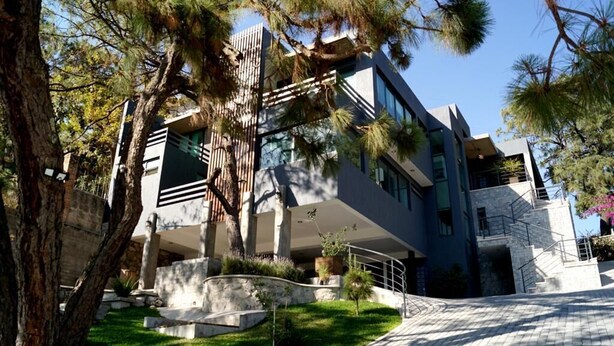 A modern building with a stone facade, large windows, and a well-maintained lawn.