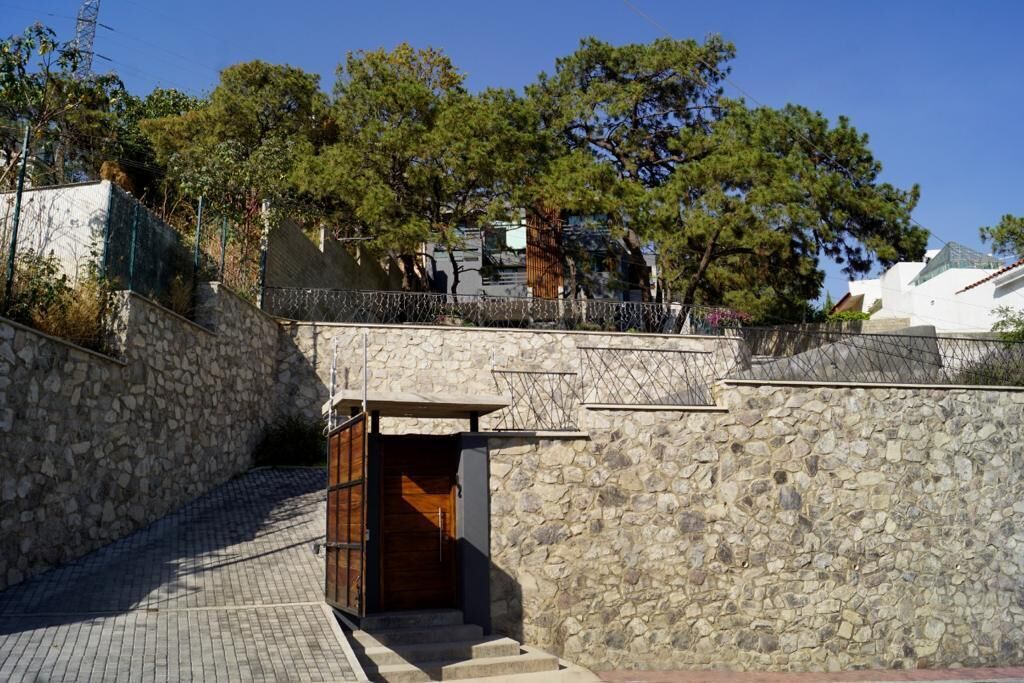 A stone-walled building with a wooden door and steps leading up to a gated entrance.