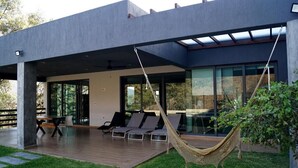 A modern house with a covered patio, outdoor seating, and a hammock.