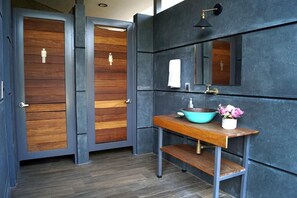 Een badkamer met houten deuren, een wastafel met kom, een spiegel en een handdoekhouder.