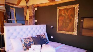 A bedroom with a large bed, a wooden ceiling, and a framed painting on the wall. - Cities Of the World - Cusco City Views (Cusco)