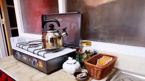 Une cuisine équipée d’une cuisinière à gaz, d’une bouilloire et de divers ustensiles de cuisine.
