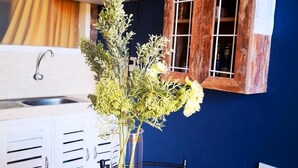 A kitchen with white cabinets, a wooden cabinet with a window, and a vase with flowers on a table.
