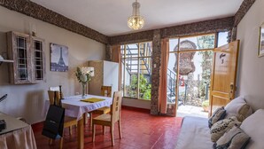 Una habitación con una mesa de comedor, sillas, una cama y vistas a un jardín a través de un gran ventanal.