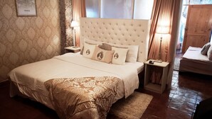 Un dormitorio ordenado con una cama grande, una mesita de noche, una lámpara y un cuadro en la pared.