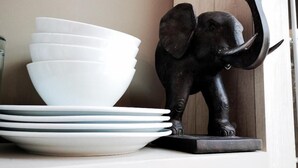 Una pila de platos blancos y una estatua de elefante negro sobre una estantería.