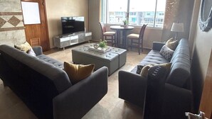 Una sala de estar con sofá, reposapiés y un comedor con sillas y mesa.