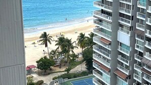 Un edificio alto con varios balcones que dan a una playa y una zona de piscina.