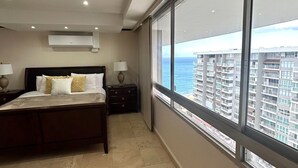 Un dormitorio con un ventanal grande, una cama, una mesita de noche y un equipo de aire acondicionado.