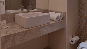 A modern bathroom with a large sink, a mirror, and a shower. - Mar Premier Flats (Queimados)