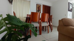 Ein Essbereich mit Holzkästen und einem Tisch, einem braunen Sofa und einer großen, grünen Pflanze.