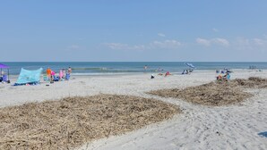 Une plage avec des gens, des tentes et des chaises de plage.