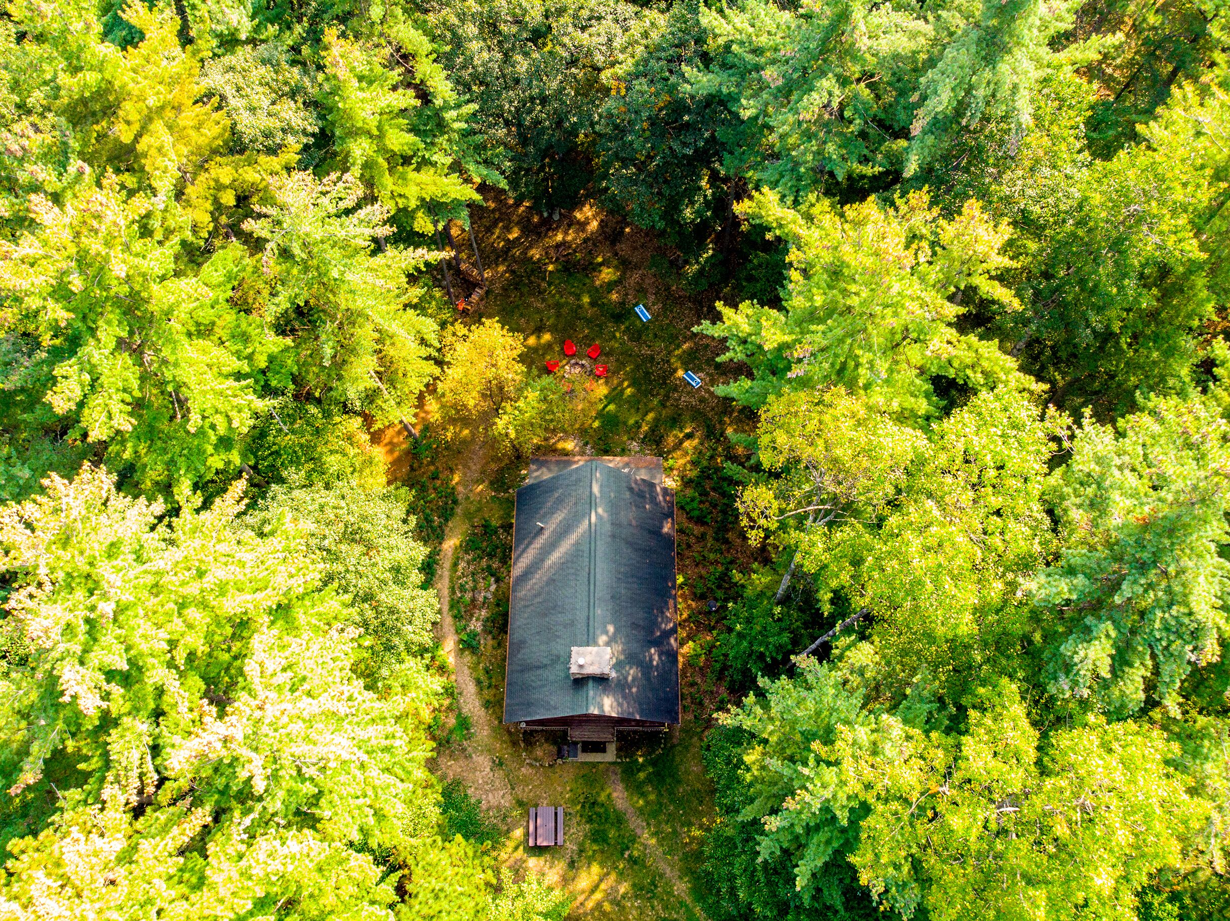 Vue aérienne d’une maison entourée d’une forêt dense et verdoyante.