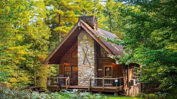 A rustic cabin with a stone facade, wooden deck, and a porch with seating. - Luxury ADK Retreat Near Whiteface, Lake Placid (Jay)