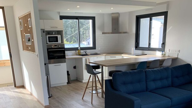 A modern kitchen with a dining area, a blue sofa, and a bench. - Contemporary house at the gates of Brest (BOHARS)