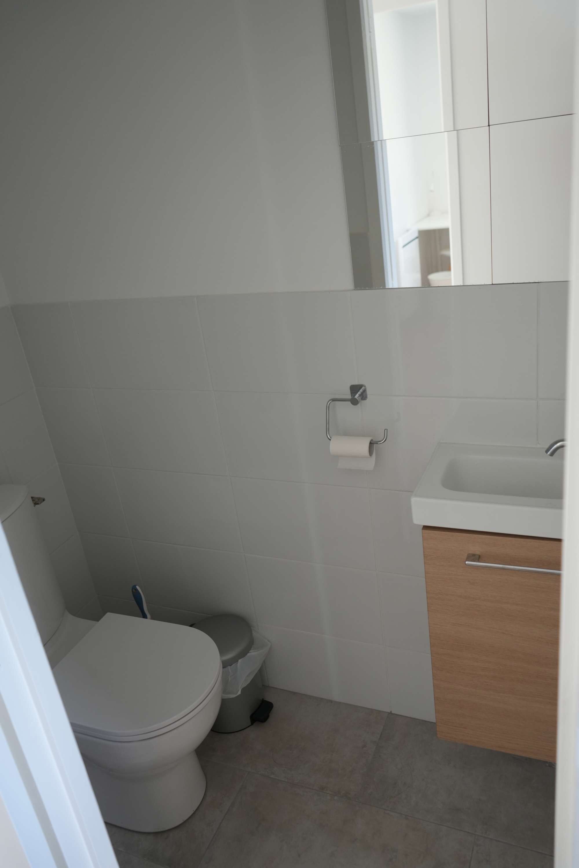A small, clean bathroom with a toilet, sink, and storage cabinet.