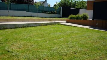 A well-maintained grassy yard with a concrete pathway leading to a modern building.