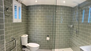 Un baño moderno con cabina de ducha curva, inodoro y mampara de vidrio.