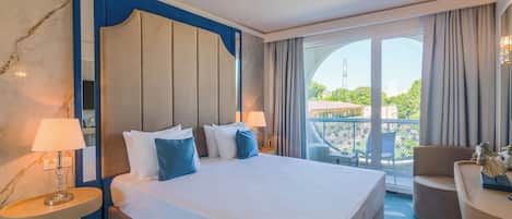 A hotel room with a large bed, two bedside lamps, a view of the outdoors, and a balcony with a chair.