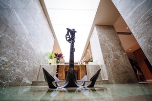 A lobby with a marble floor, a central sculpture, and a ceiling with skylights.