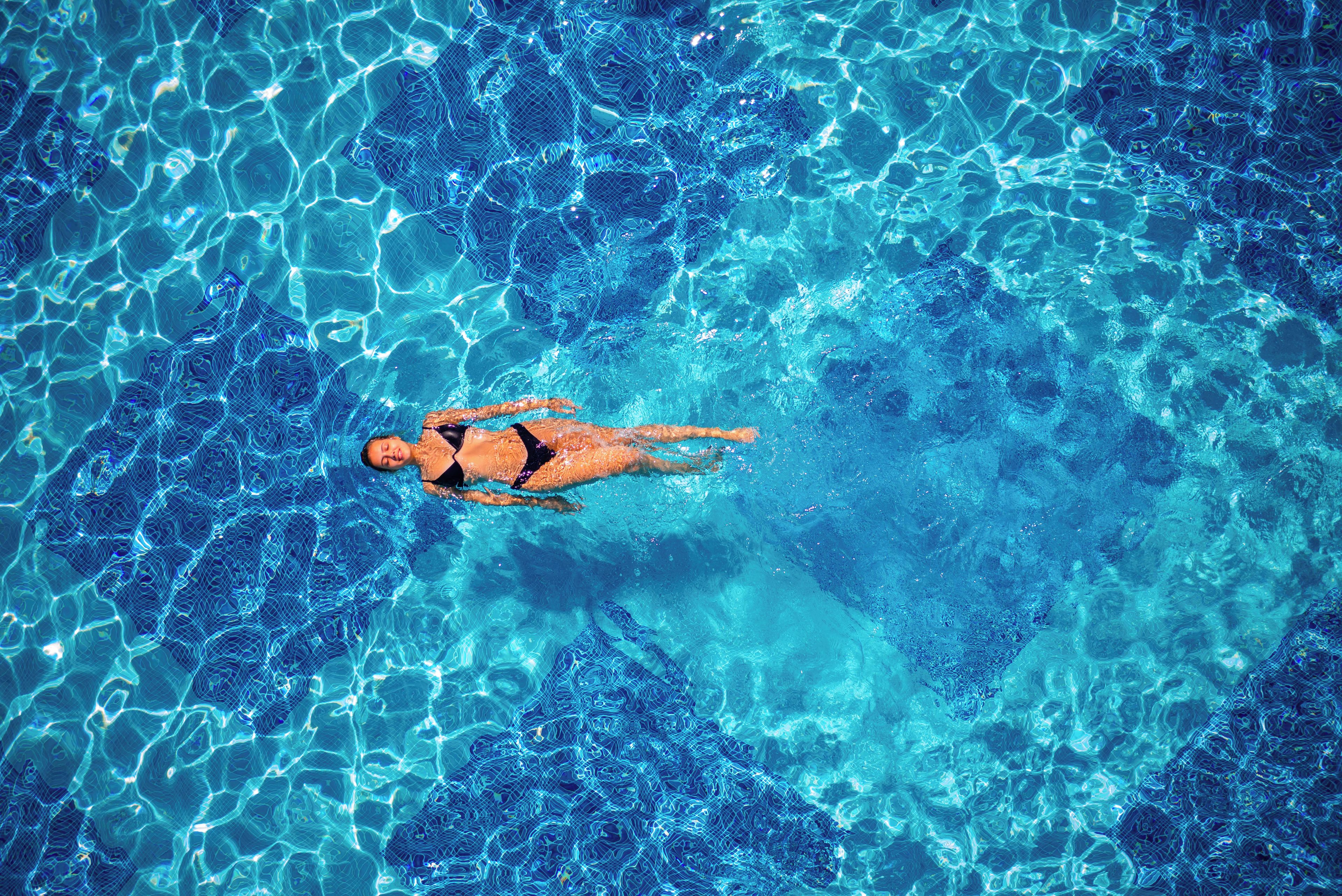 A person swimming in a pool with clear blue water.