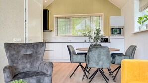 A modern kitchen with white cabinets, a built-in oven, and a window with blinds.