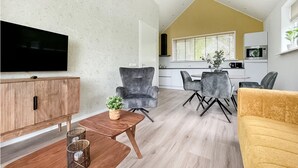 A modern living room with a flat-screen TV, a wooden cabinet, and a yellow sofa.