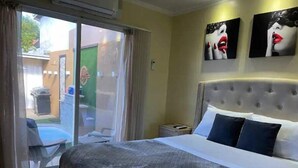 A hotel room with a large bed, a nightstand, and a view of the outside. - Arupar Apartment (PARADERA)