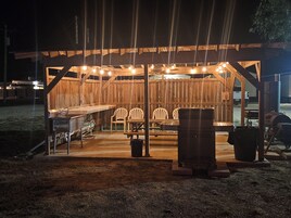 Una estructura de madera al aire libre con una zona de bar, asientos y una parrilla.