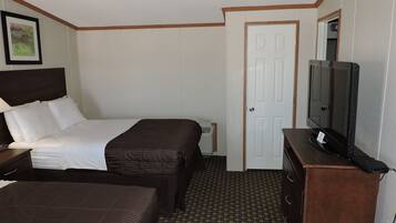 Une chambre d’hôtel avec deux lits, une télévision, une commode et une porte.